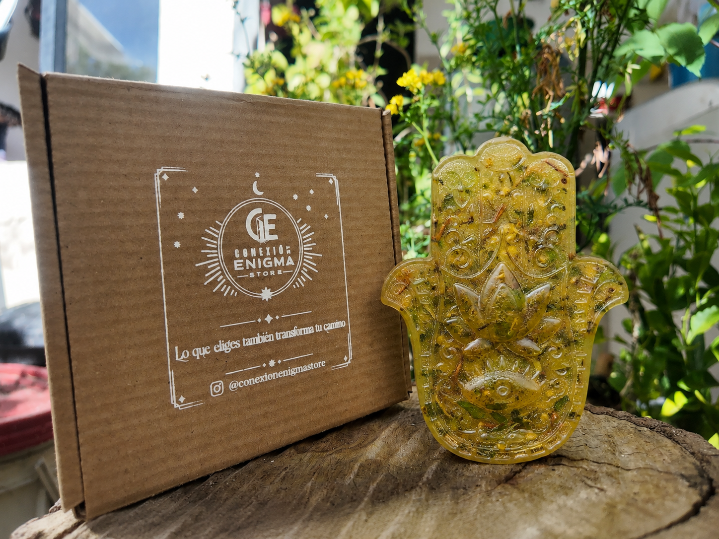 Jabón artesanal Baño de 7 Hierbas Dulces, de color amarillo y con forma de mano de Fátima, presentado junto a su caja de Conexión Enigma Store.